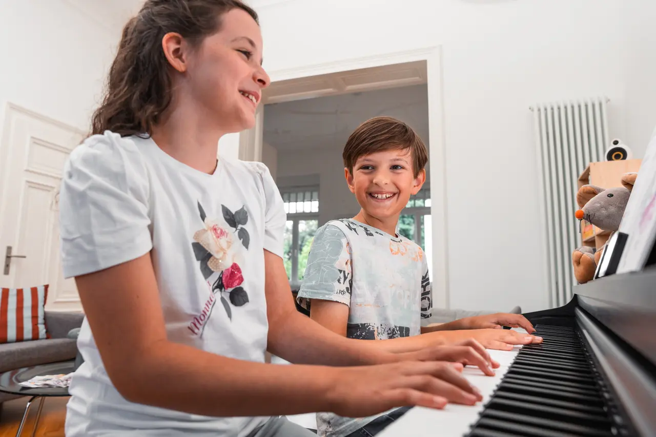Une femme et un garçon sont assis ensemble, souriant devant un piano numérique.