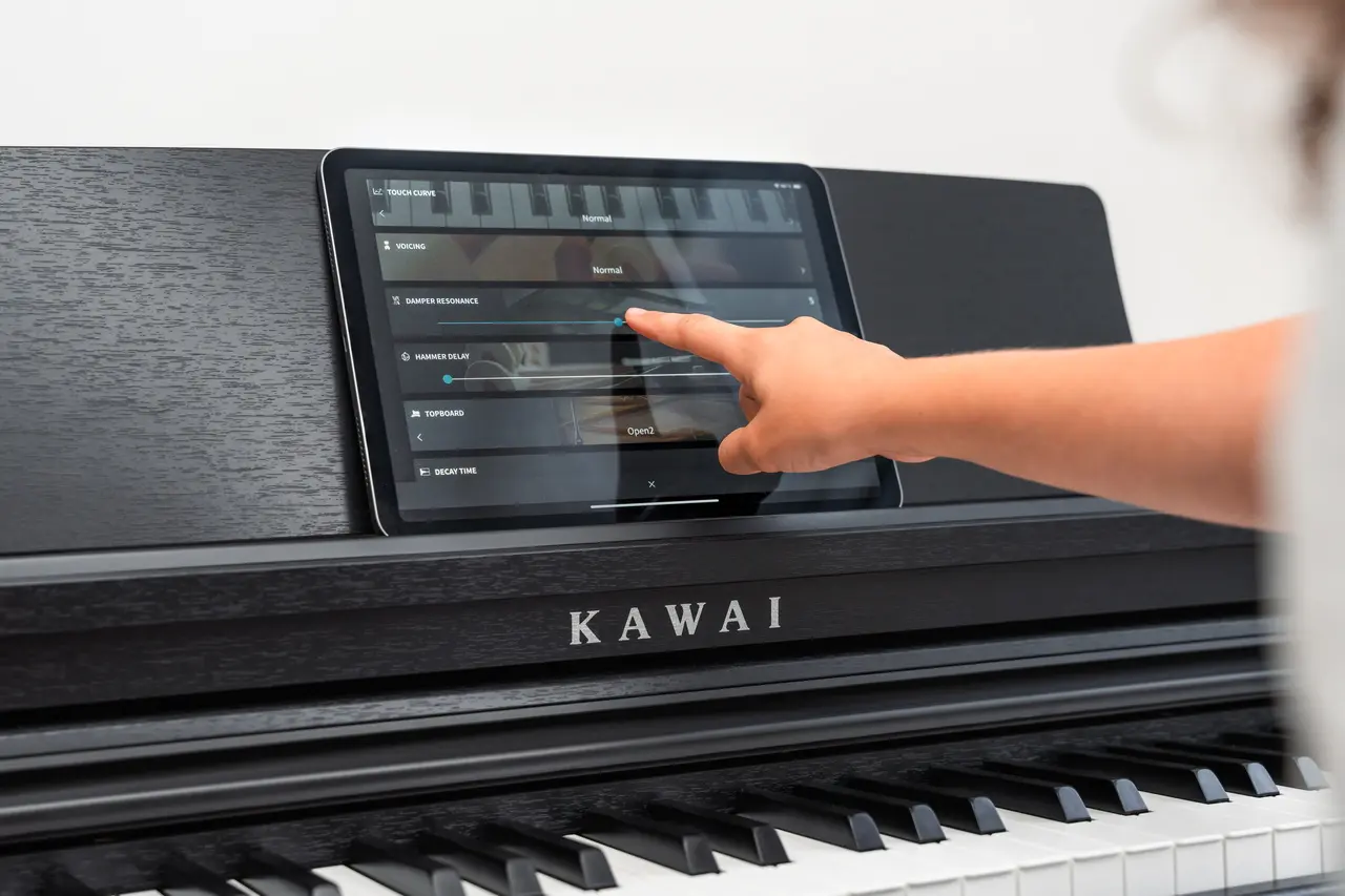 La main actionne l’affichage d’un piano numérique Kawai noir.